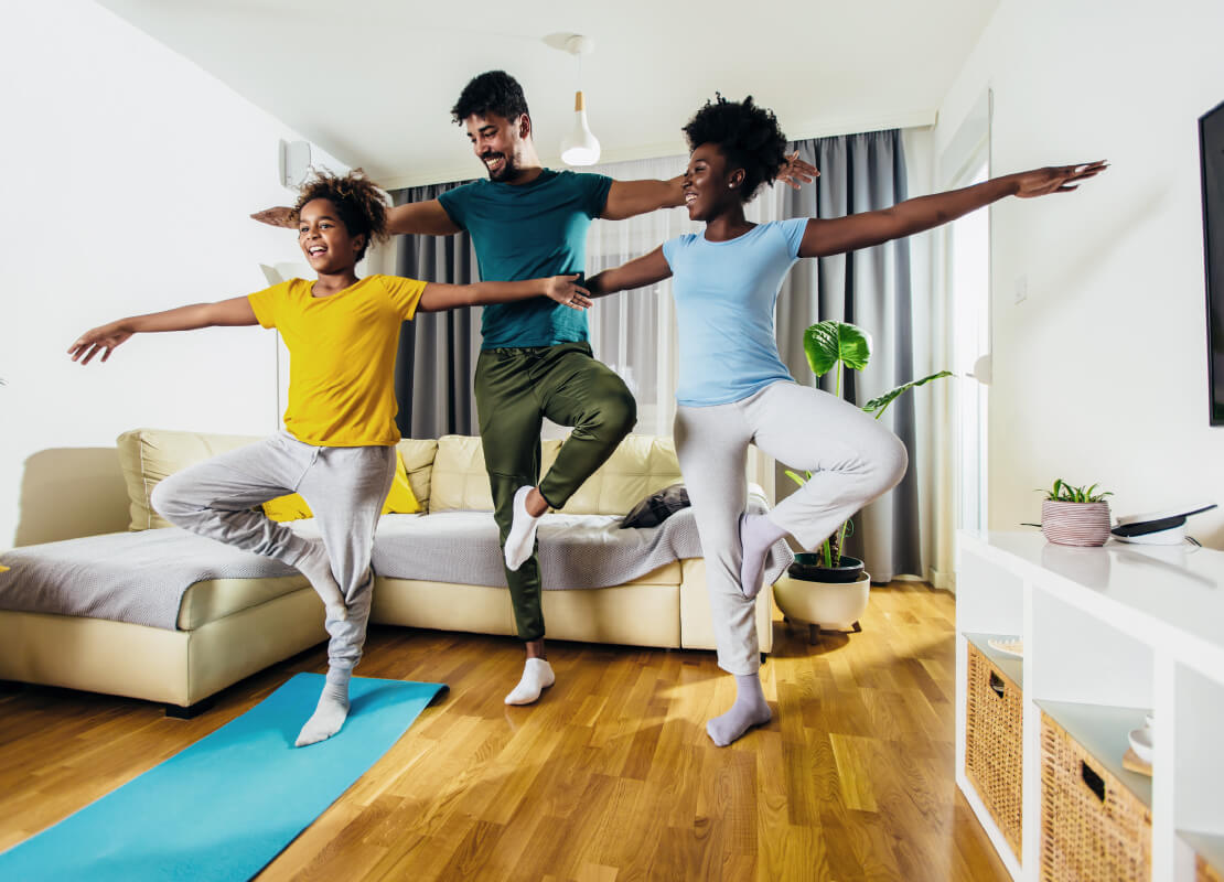 Family of three doing yoga in family room, smiling